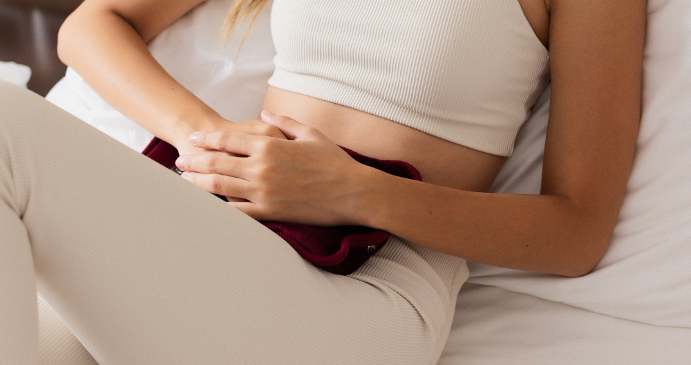 Person with adenomyosis laying down with a heated water bottle