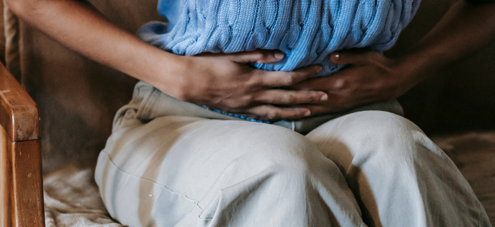 Person leaning over and holding their abdomen due to chronic pelvic pain