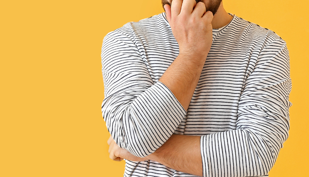 Person standing in front of a yellow background looking concerned