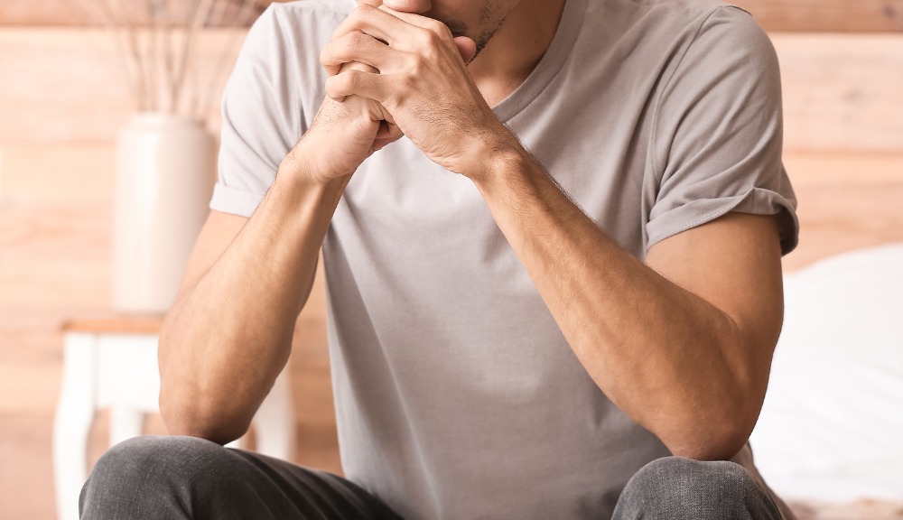 Person sitting alone and thinking with their hands clasped together