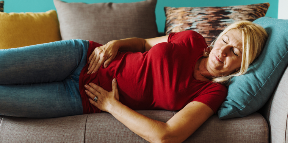 person lying down on a couch holding their pelvis