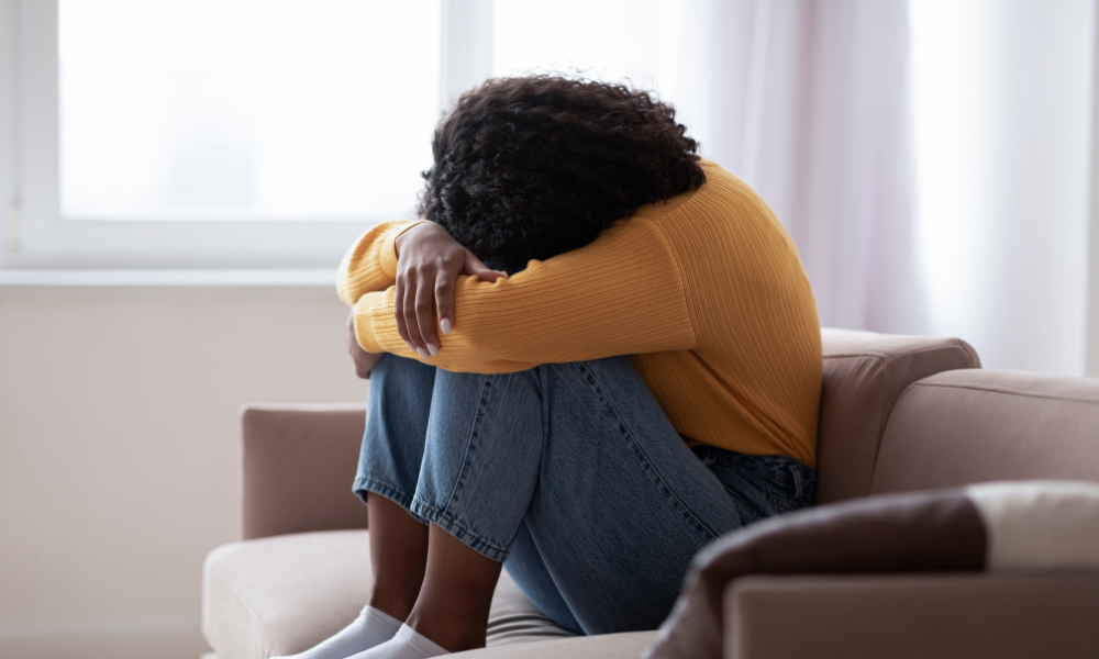 Frustrated person sitting with their head resting on their knees