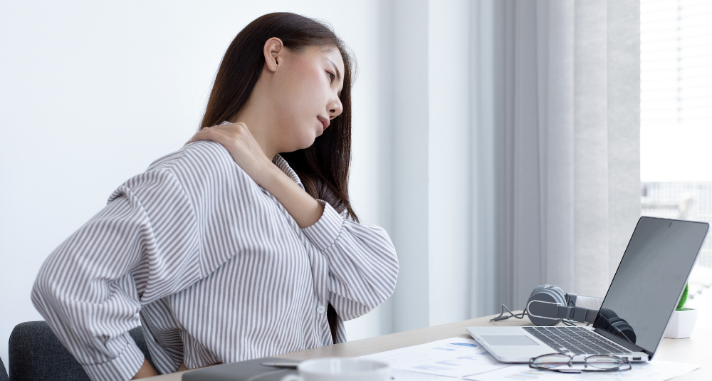 Person sitting at a desk and experiencing shoulder pain