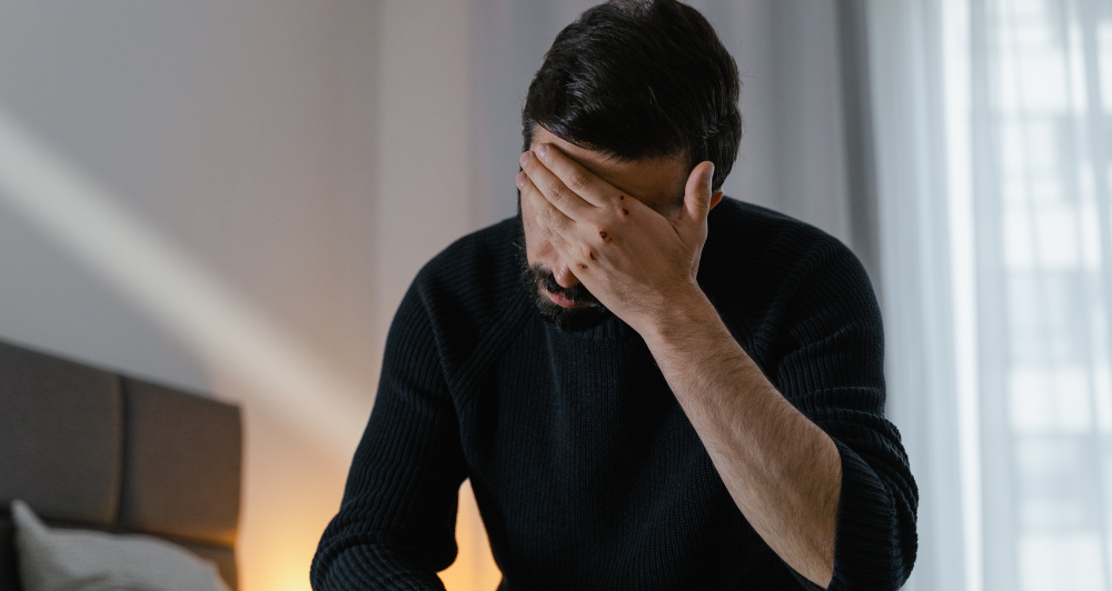 man sitting with his hand to his face in frustration