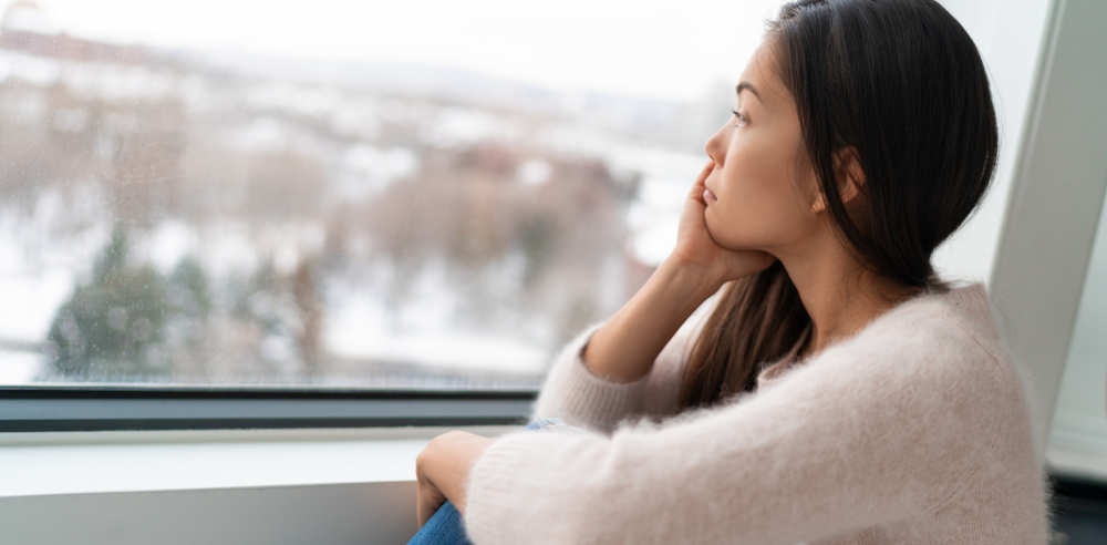 Person sorrowfully looking out of a window